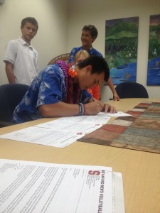 Evan Enriques signs his letter of intent on Wednesday afternoon. (Photo courtesy of Nelson Wong / Kamehameha-Hawaii Athletic Department)