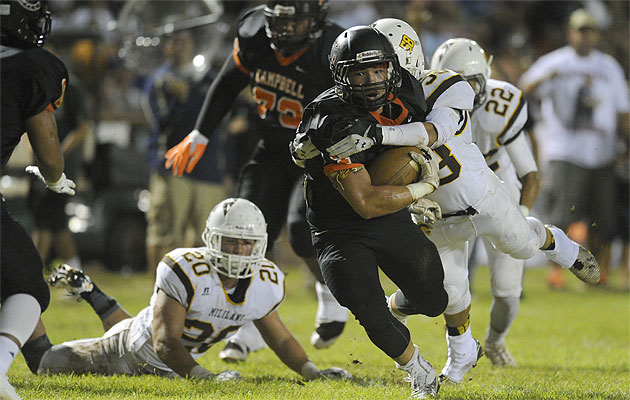 Campbell's Austin May gained yardage before being stopped by Mililani's Sergio Urena on Friday. Bruce Asato/Star-Advertiser.