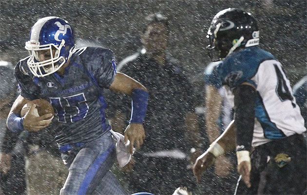 Moanalua quarterback Kawika Keama-Jacobe dodged a heavy rain along with Kapolei defenders on Friday night. (Honolulu Star-Advertiser/Jamm Aquino.