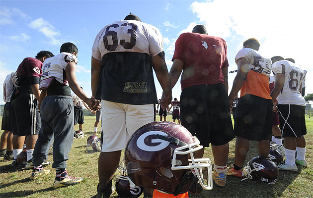 Farrington HS players gather on the field for an opening prayer before starting football practice at the school's field. Bruce Asato / Star-Advertiser