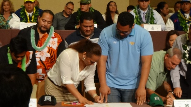 Punahou offensive lineman Semisi Uluave watches as his mother signs his letter of intent. (Photo: Paul Honda)