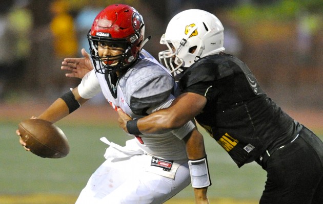 Kahuku moves from the OIA Red to the OIA Blue in the league's realignment for 2016. Mililani goes from the Blue to the Red. Pictured, the Trojans' Tyrell Niuatoa sacked the Red Raiders' Jordan Mariteragi in a July 31 scrimmage. Bruce Asato / Honolulu Star-Advertiser.