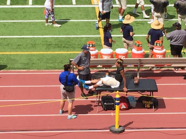 Promising young two-sport player Cole Arceneaux being treated on the sideline after getting hit from behind during a play. 
