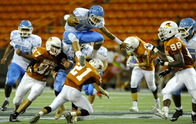 St. Francis' Wembley Mailei jumped over Pac-Five's Casey Nakamura on his way to a big gain during the Saints' 12-9 win at Aloha Stadium on Friday. Mailei was penalized on the play for hurdling another player. Bruce Asato / Honolulu Star-Advertiser.