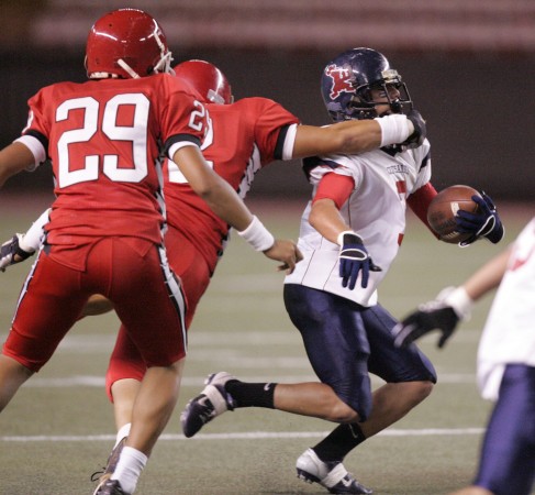 Saint Louis' Lucas Gonsalves tried to elude Kahuku's Triton Oto. Photo by Richard Walker/Star-Bulletin.