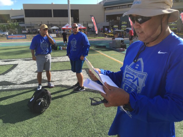 Pearl City head coach Robin Kami scans the five-page itinerary for the GPA Football College Showcase. Hilo head coach Kaeo Drummondo (center) and Kami are among the volunteer coaches at the three-day event. 