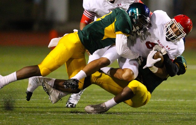 Leilehua's Charles Watson, left, and Kendrick Beitzel brought down Kahuku running back Harmon Brown during the Red Raiders' 49-15 win on Aug. 12.  The two teams play again in the OIA quarterfinals Friday night. Jamm Aquino / Honolulu Star-Advertiser.