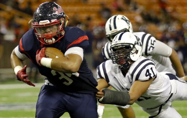 Saint Louis' Austin Tuisano tried to escape the grasp of Kamehameha defensive end Jonah Welch. Photo by Jamm Aquino/Star-Advertiser.