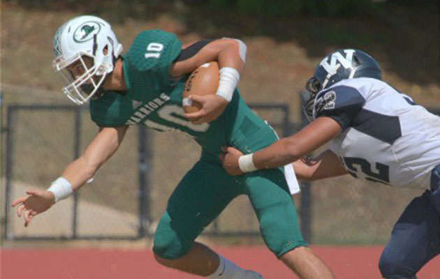 Kapaa senior quarterback Kurt Napoleon attempted to escape the clutches of Waimea linebacker Waika Corr in a Sept. 24 game. The Warriors missed a chance to clinch the Kauai Interscholastic Federation title by losing 20-17 to Kauai. Photo courtesy of KauaiSports.com.