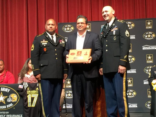 Saint Louis School president Glenn Medeiros accepts a plaque for the school from the US Army All-American Bowl. 