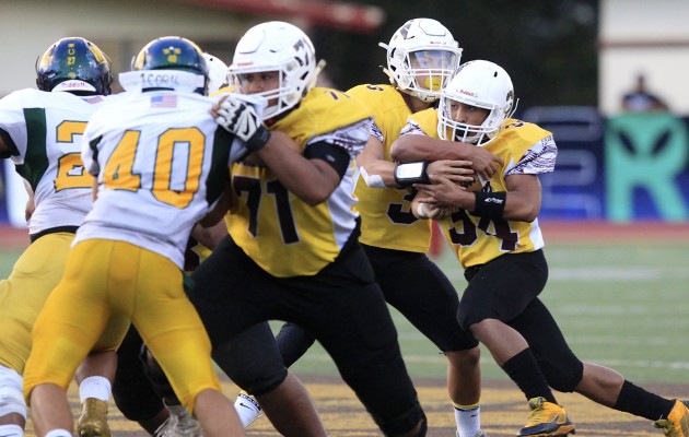 Mililani quarterback Dillon Gabriel handed the ball off to running back Fabian Johnson-Slay. Photo by Cindy Ellen Russell/Star-Advertiser.