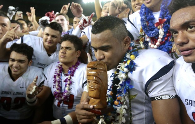 Saint Louis QB Tua Tagovailoa kissed the trophy after leading the Crusaders to a 30-14 win over Kahuku in the Open Division state final. Photo by Jamm Aquino/Star-Advertiser.