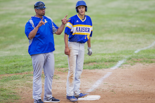 Kaiser coach Kila Kaaihue, left, flashed signs as Christian Reasoner stood on third base in the OIA East baseball opener on Wednesday between the Cougars and Kailua. Photo by Dennis Oda/Star-Advertiser.
